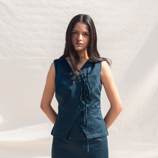 Woman wearing a dark blue sleeveless top and skirt against a white draped fabric background
