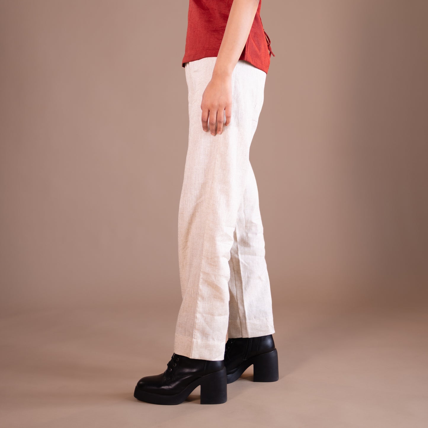 Person wearing beige pants and black shoes on a beige background