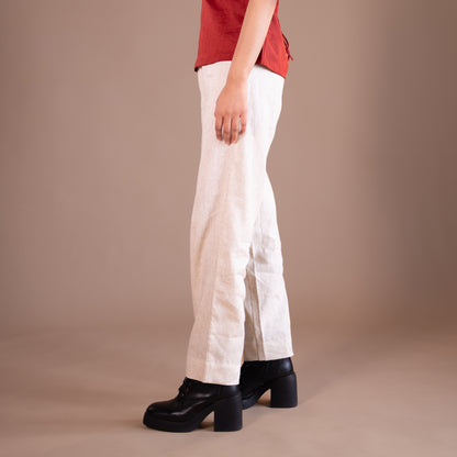 Person wearing beige pants and black shoes on a beige background