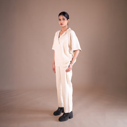 Woman wearing a beige outfit against a brown background