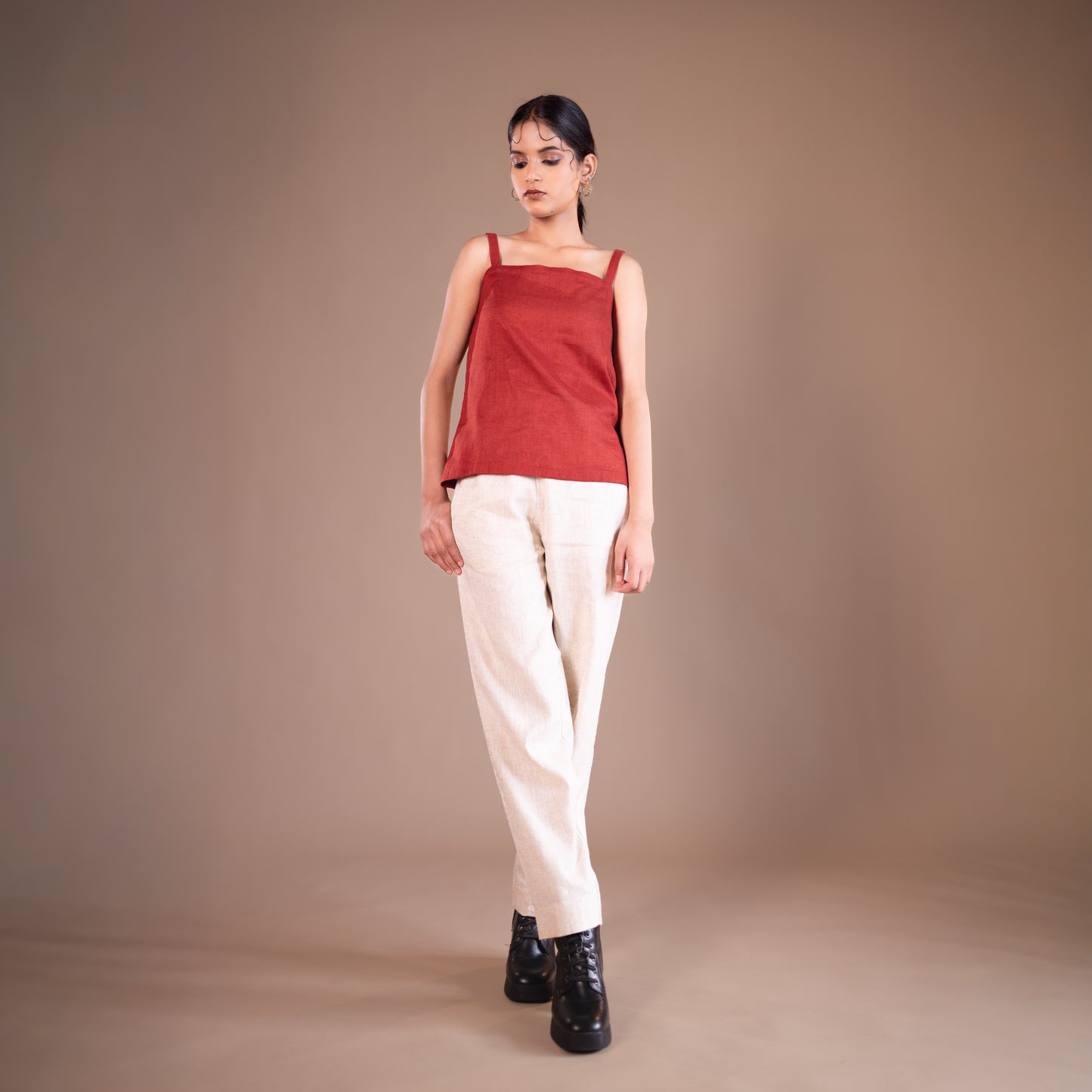 Woman wearing a red top and beige pants against a beige background