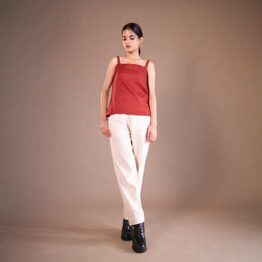 Woman wearing a red top and beige pants against a beige background