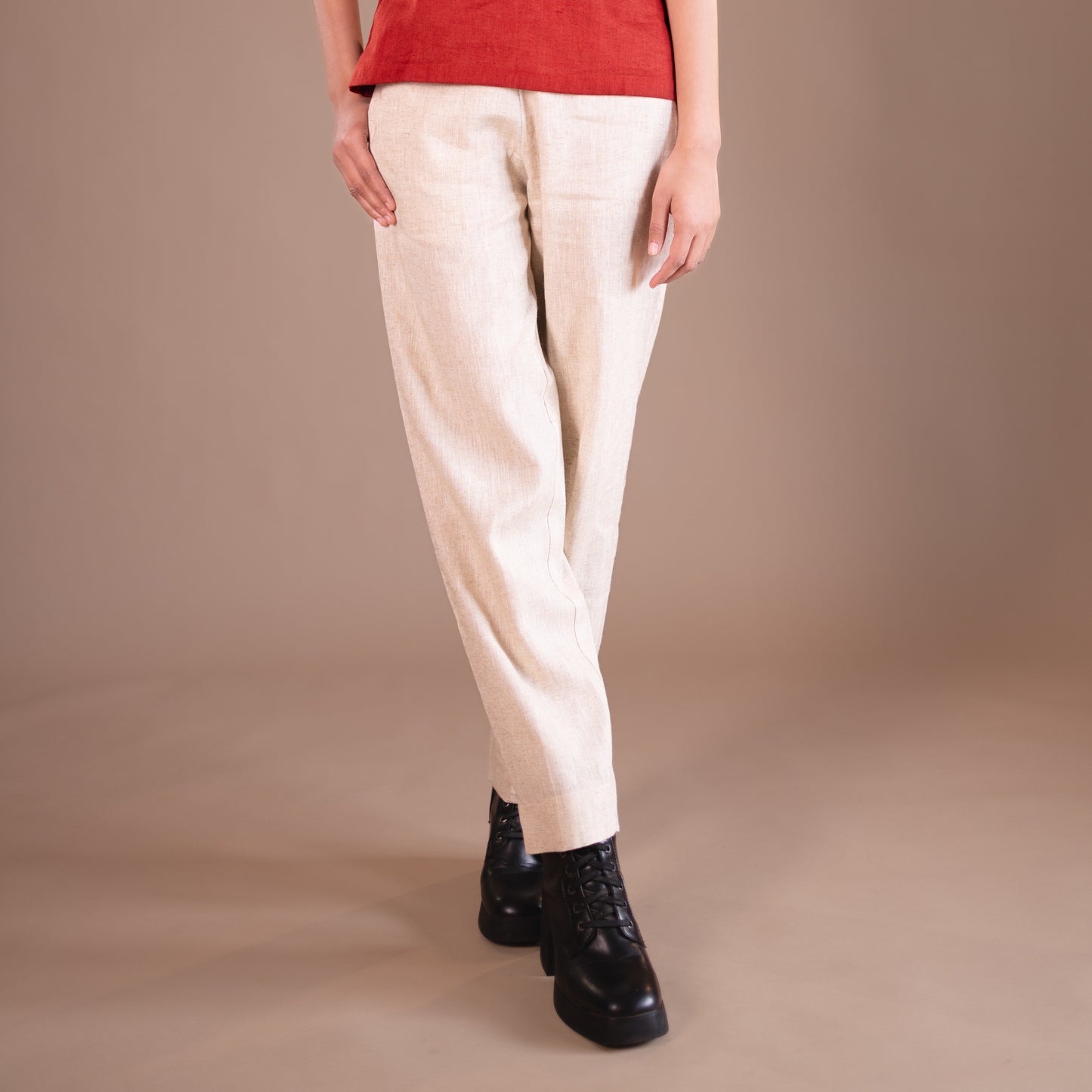Person wearing beige pants and black boots on a beige background