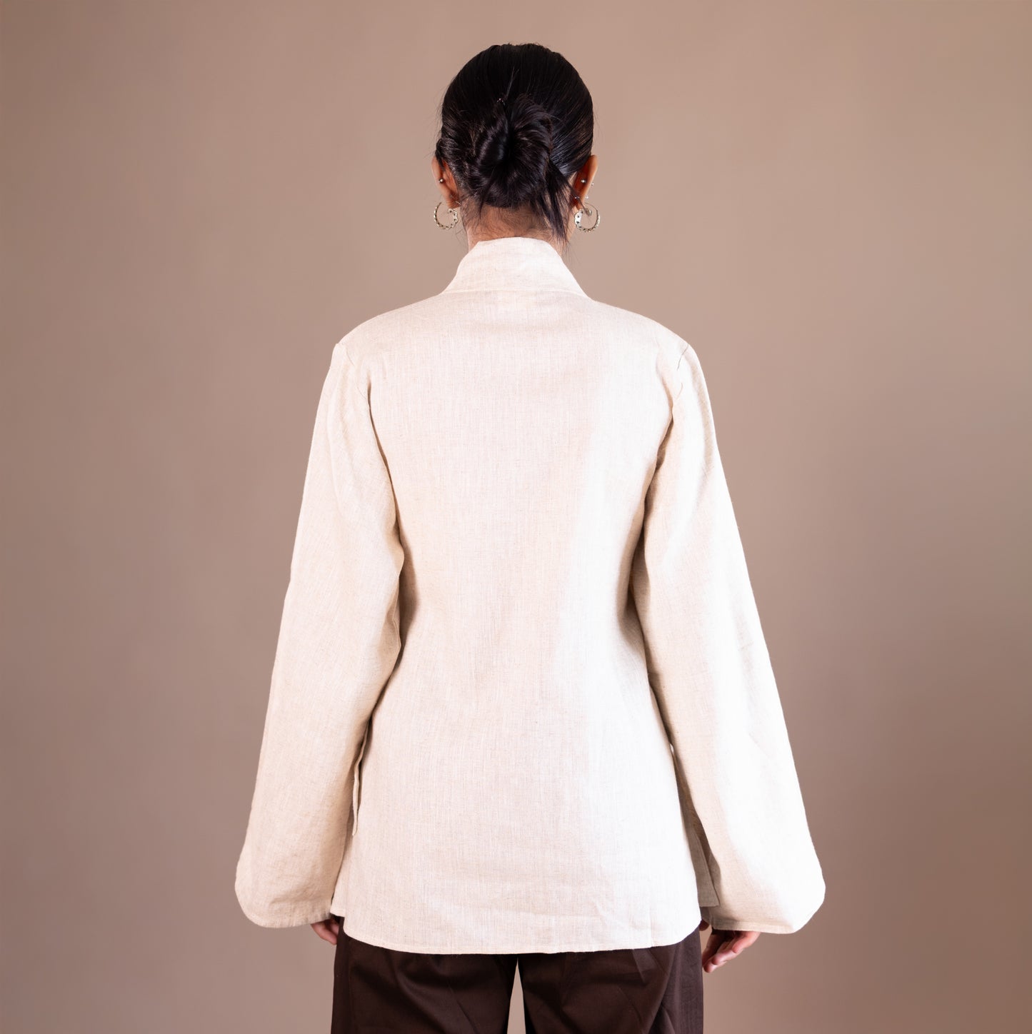 Person wearing a beige jacket on a brown background
