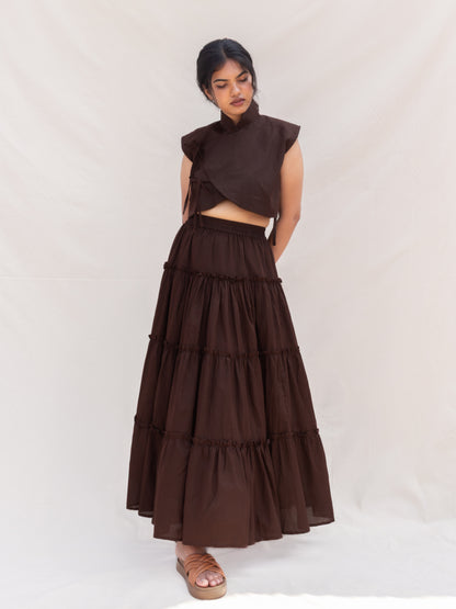 Woman wearing a brown outfit with a layered skirt on a white background