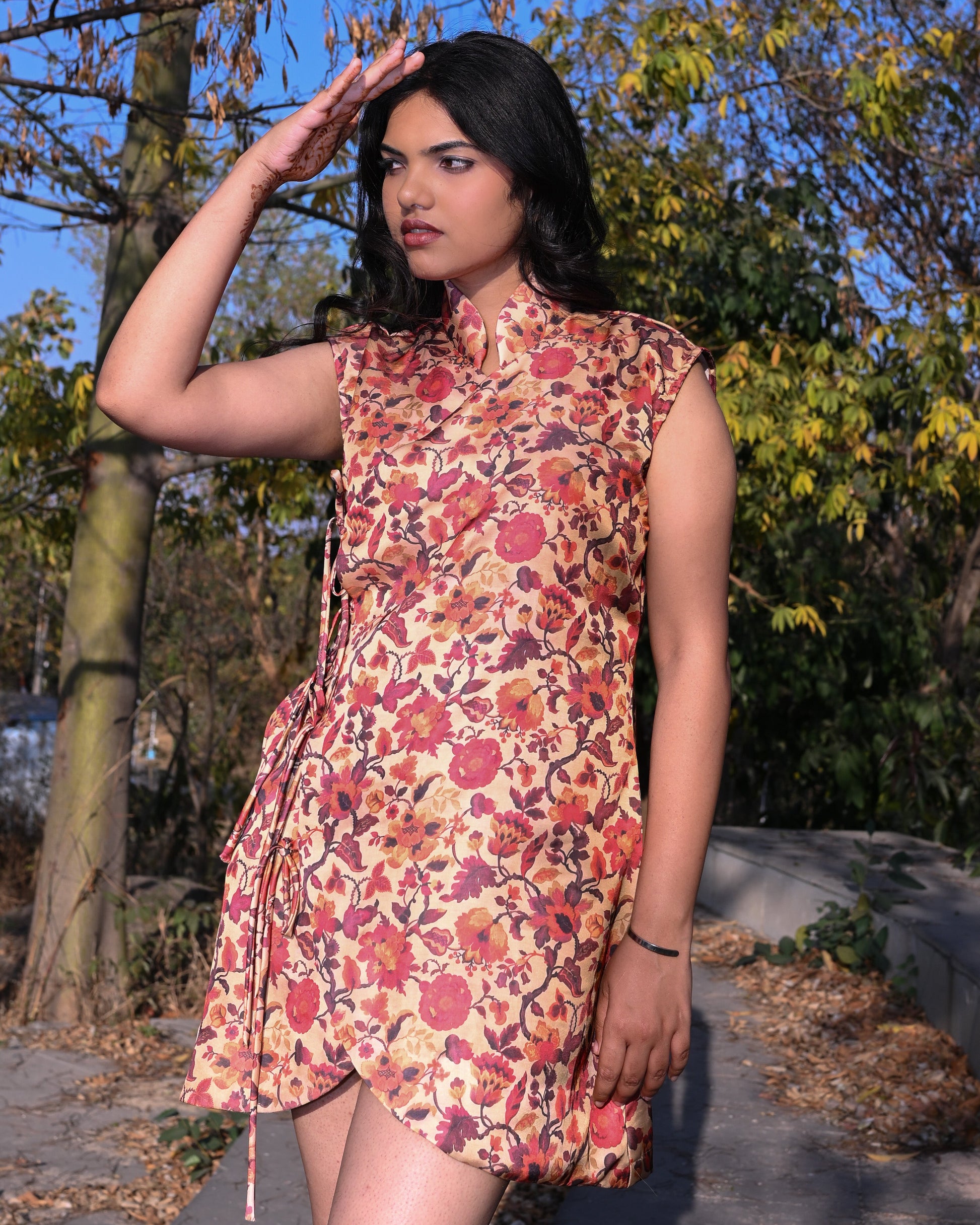 Woman in a floral dress standing outdoors with trees in the background
