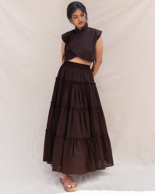 Woman wearing a brown outfit with a layered skirt on a white background
