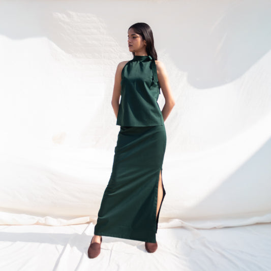 Woman wearing a green dress with a slit on a white background