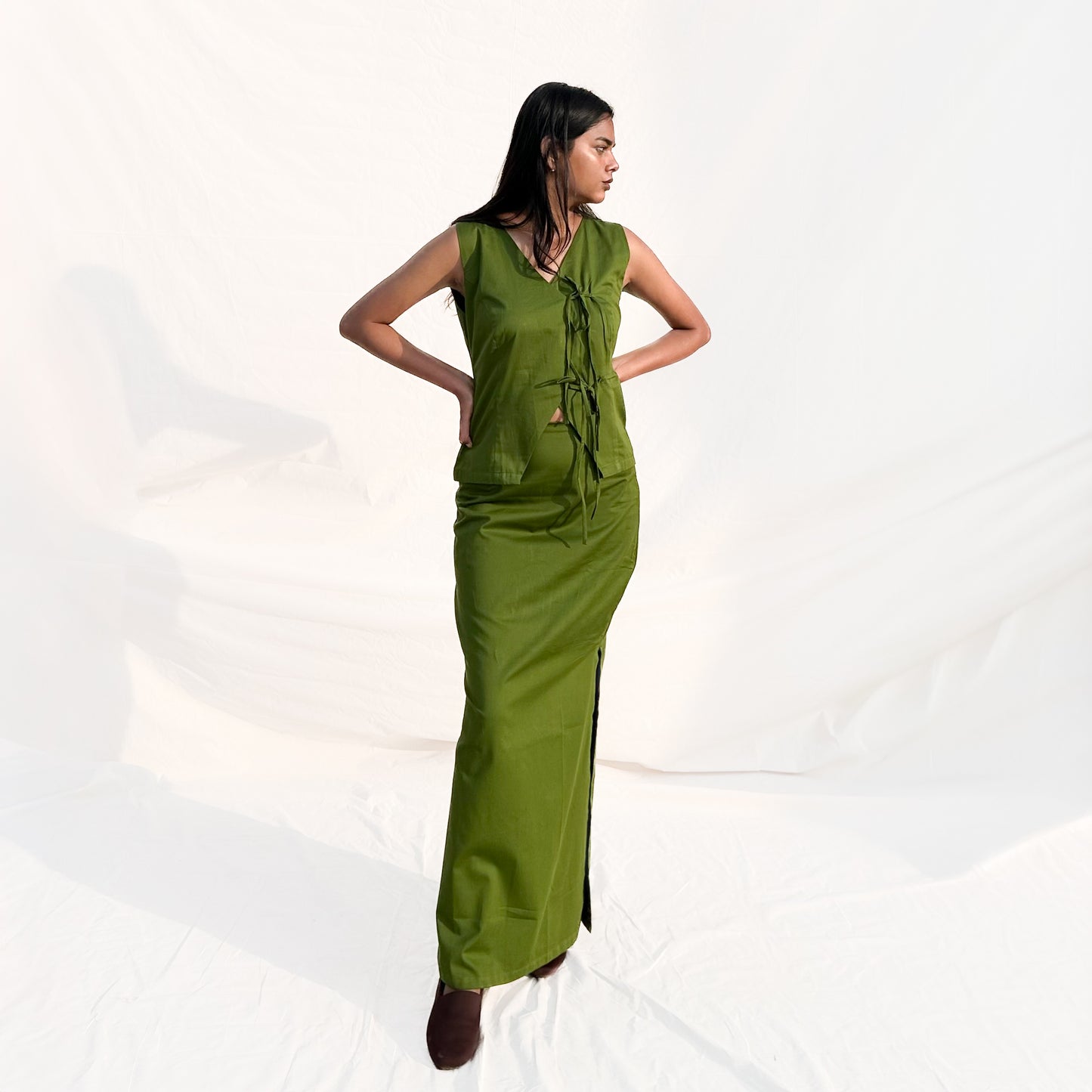 Woman wearing a green sleeveless jumpsuit on a white background