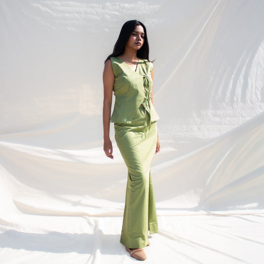 Woman wearing a green outfit standing against a white draped fabric background