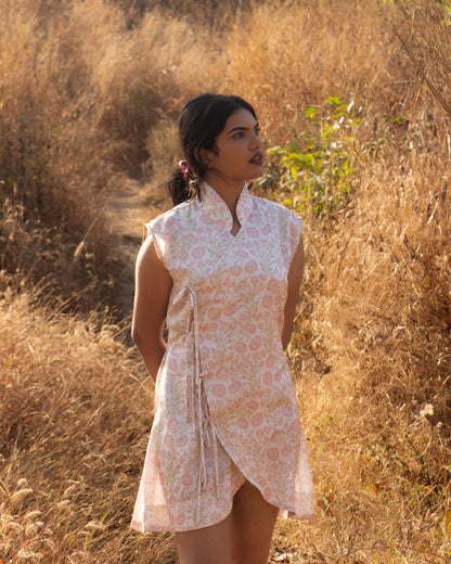 Woman in a patterned dress standing in a field of dry grass.
