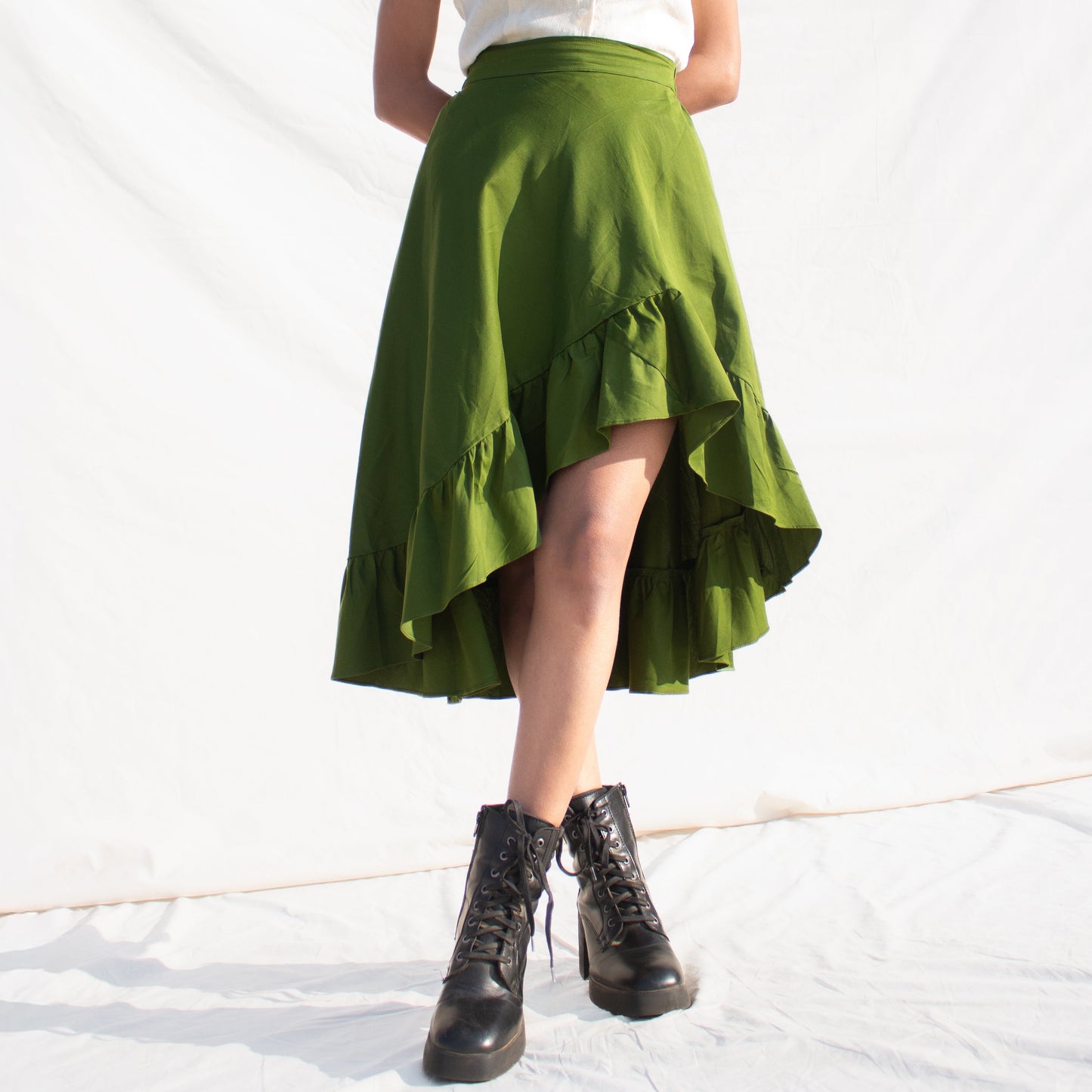 Woman wearing a white top and olive green skirt against a white background
