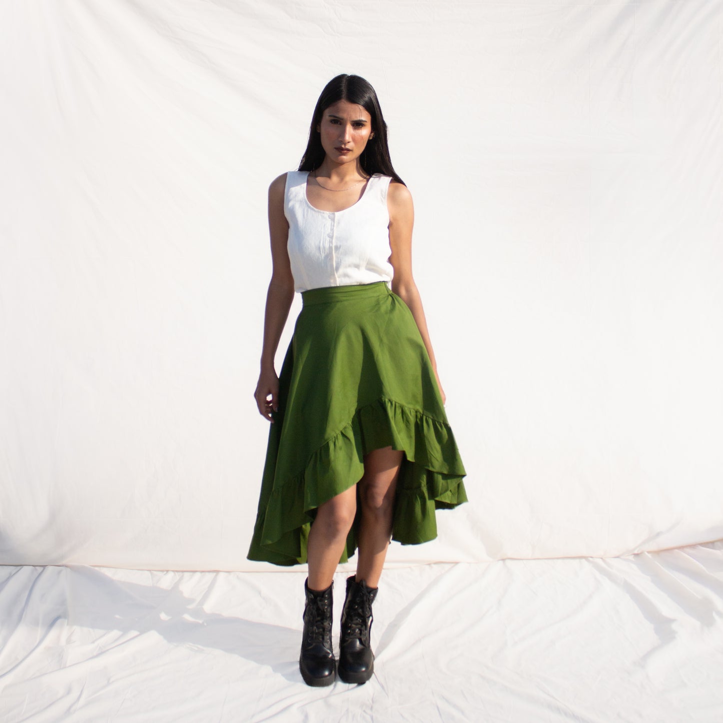 Woman wearing a white top and olive green skirt against a white background