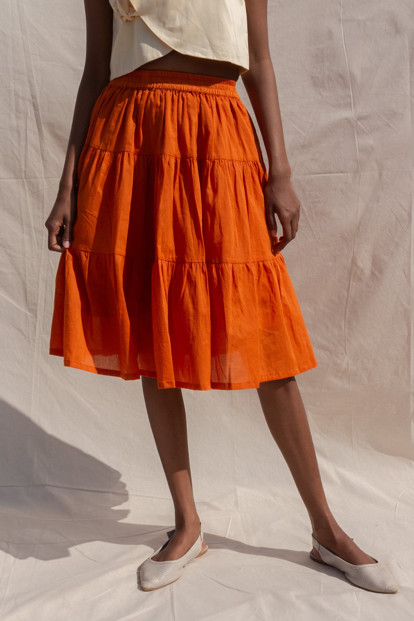 Person wearing an orange tiered skirt on a plain background