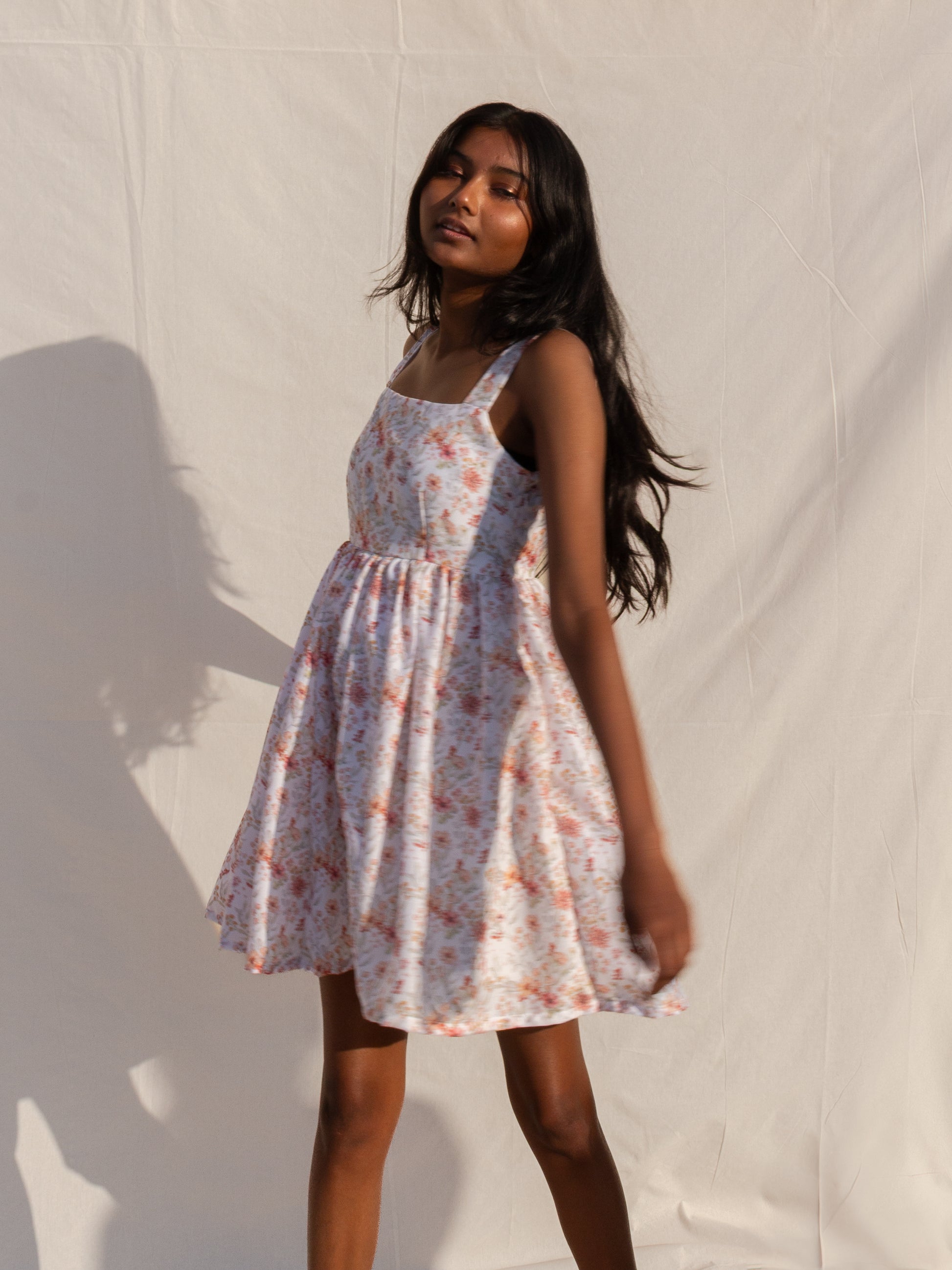 Woman wearing a floral dress against a plain background
