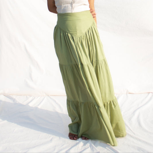 Woman wearing a white top and green skirt against a white background