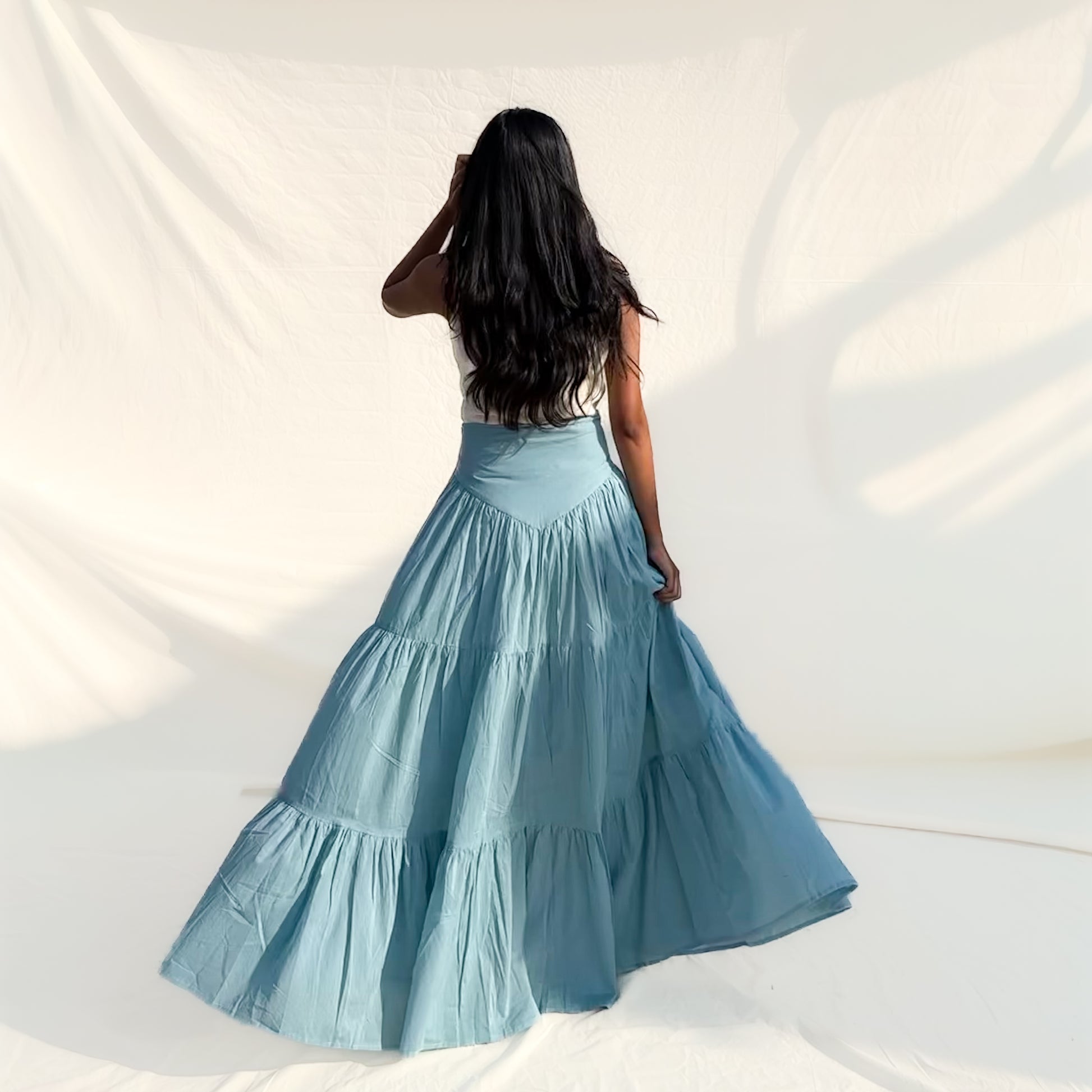 Woman wearing a blue tiered skirt against a white background