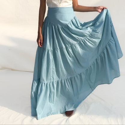 Woman wearing a light blue skirt and white top against a white background
