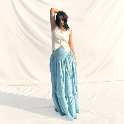 Woman wearing a white top and light blue skirt against a white background