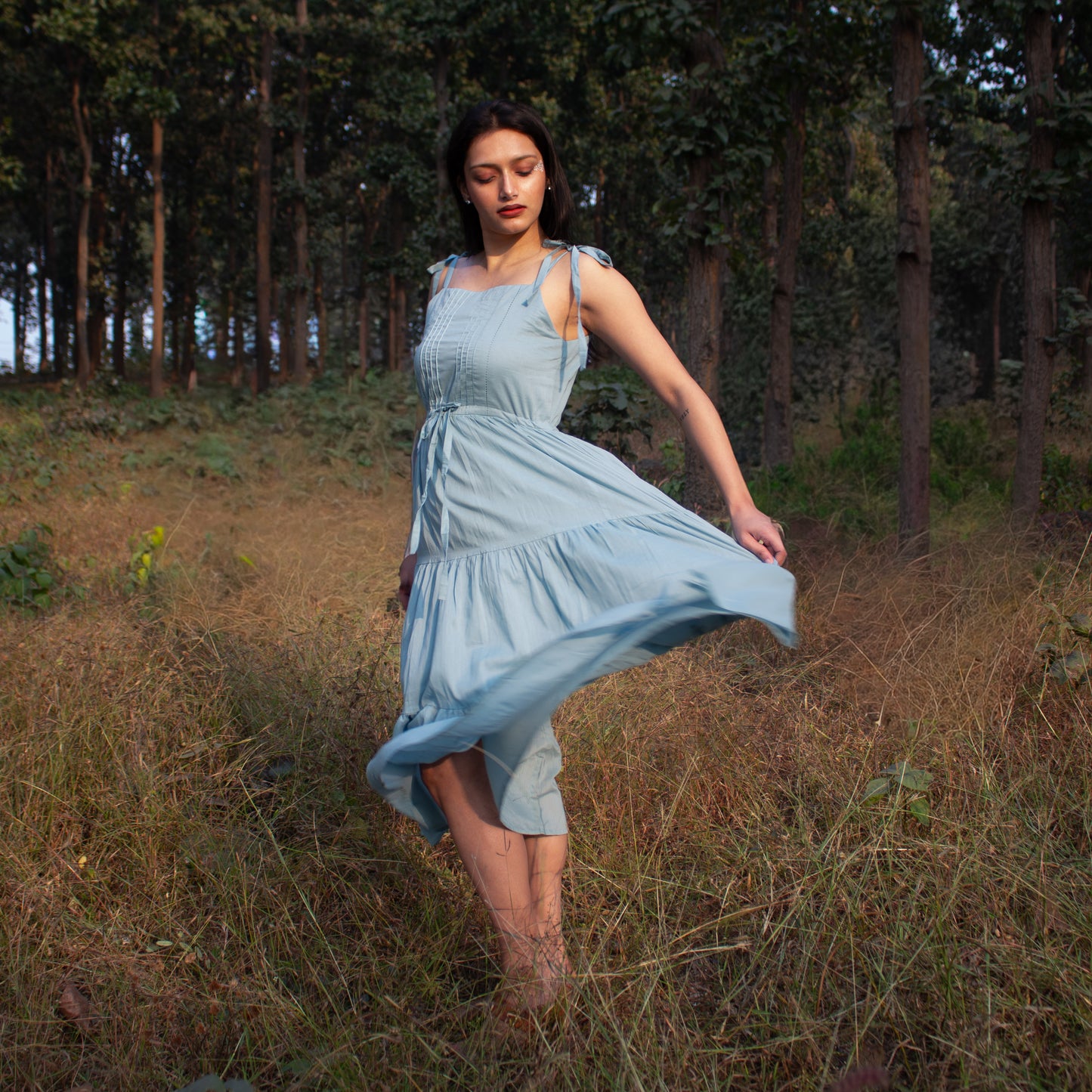 Woman in a light blue dress standing in a forest