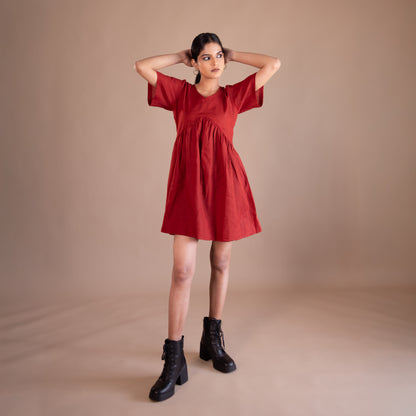 Woman wearing a red dress with black boots on a beige background