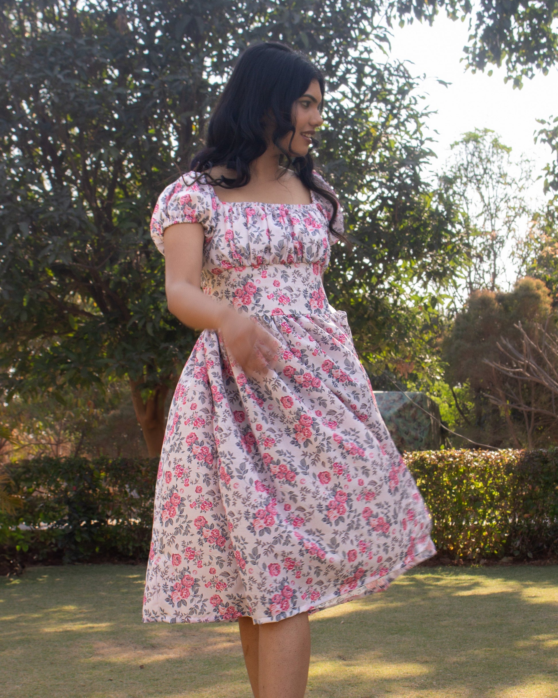 Woman in a floral dress standing outdoors with trees in the background