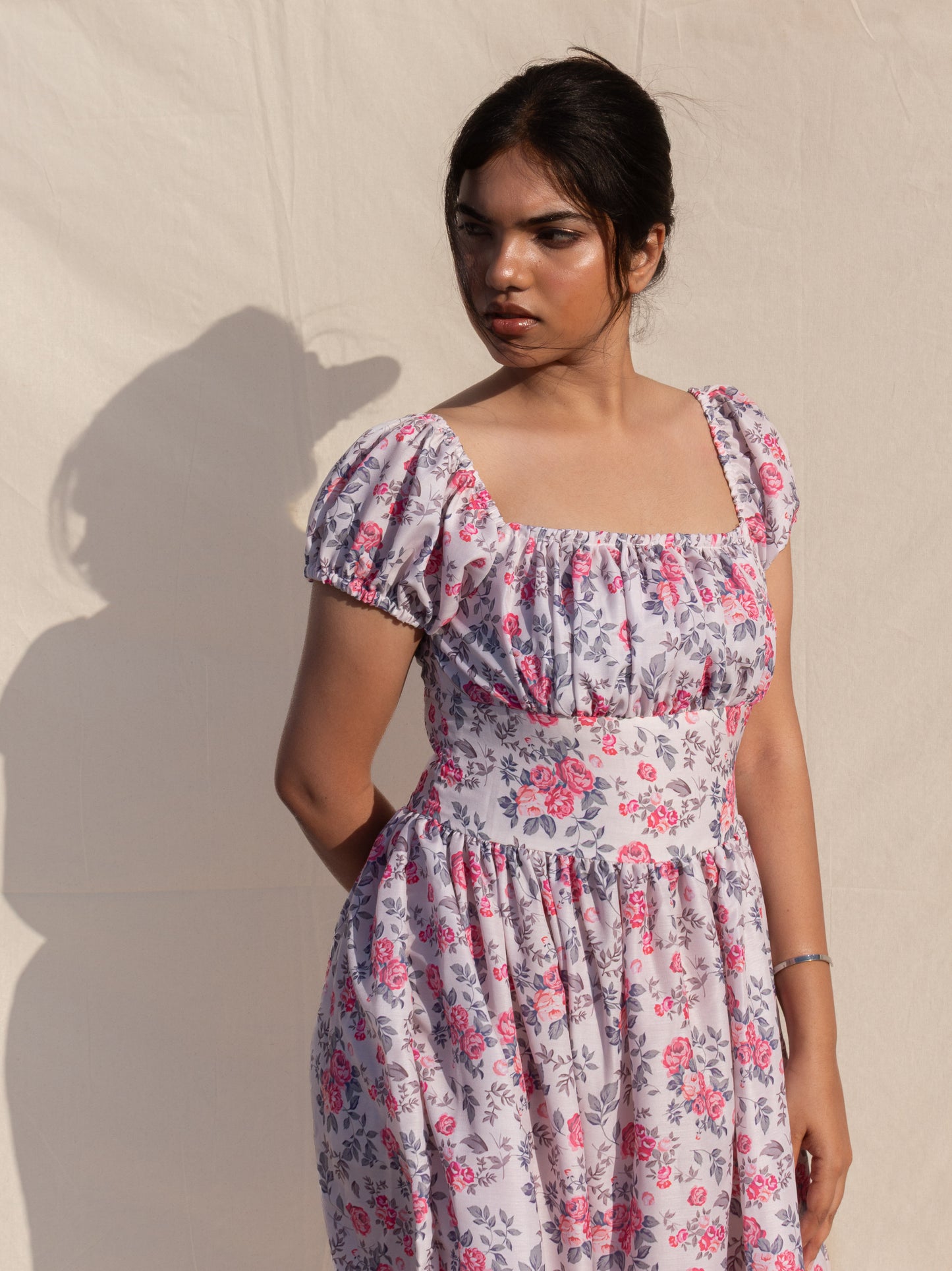 Woman wearing a floral dress against a plain background