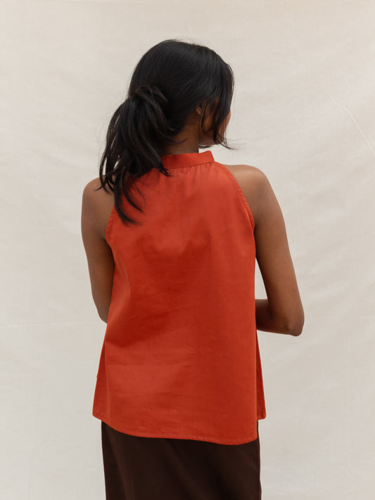 Person wearing an orange sleeveless top against a plain background