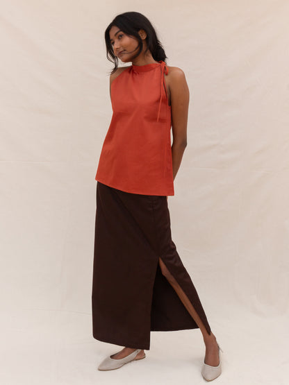 Woman wearing a red sleeveless top and brown skirt on a white background