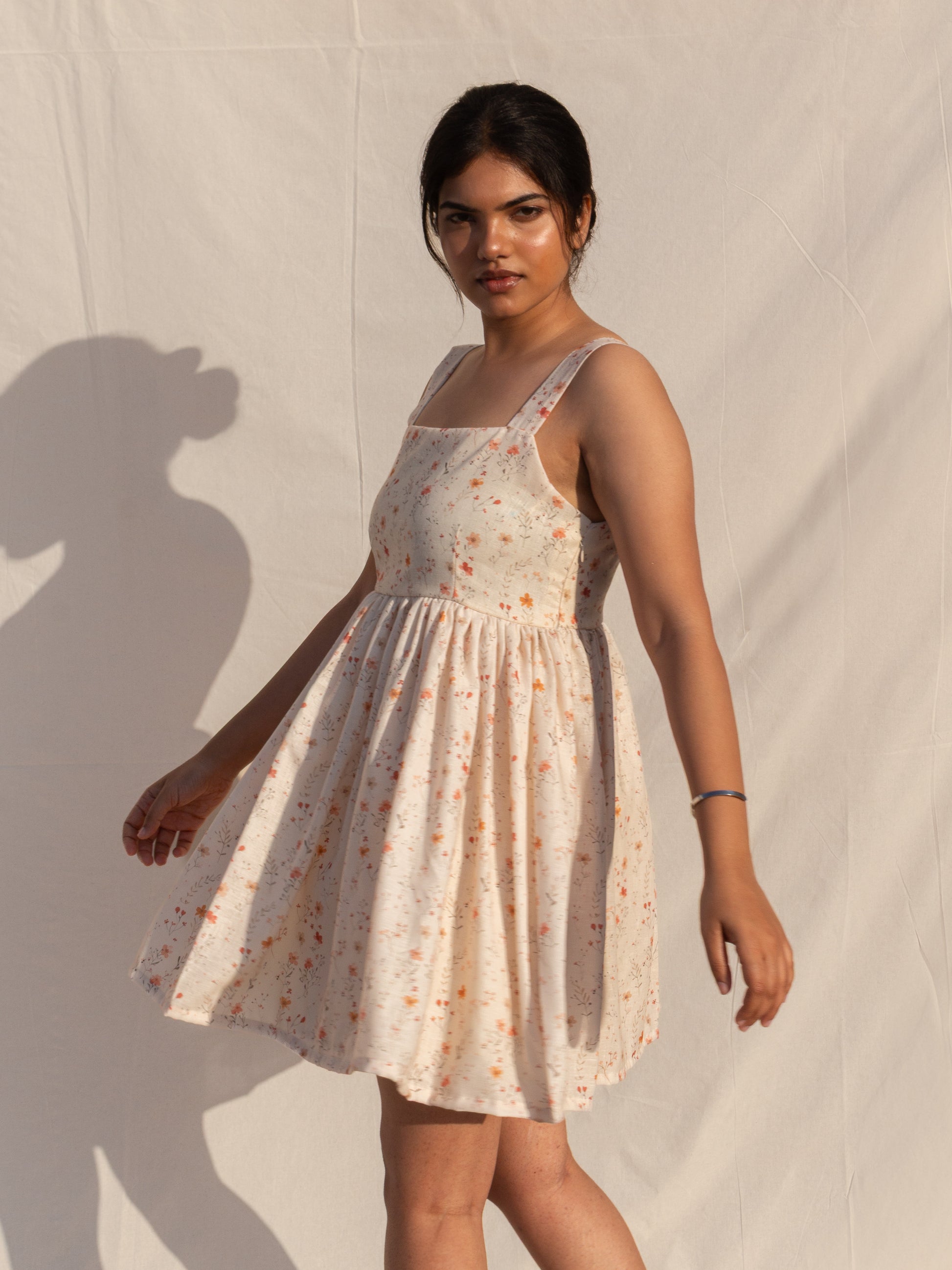 Woman wearing a floral dress against a neutral background
