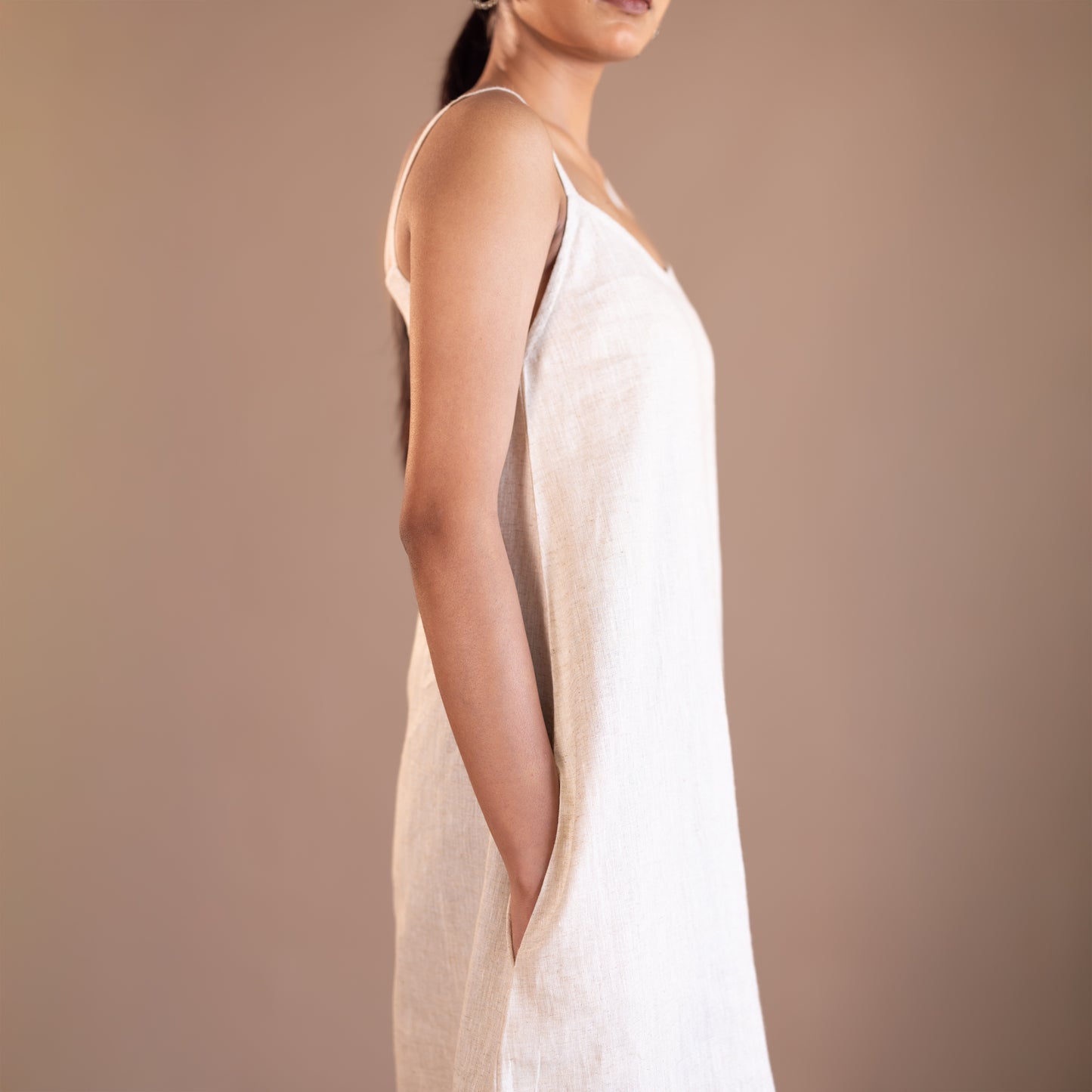 Woman wearing a beige slip dress against a brown background