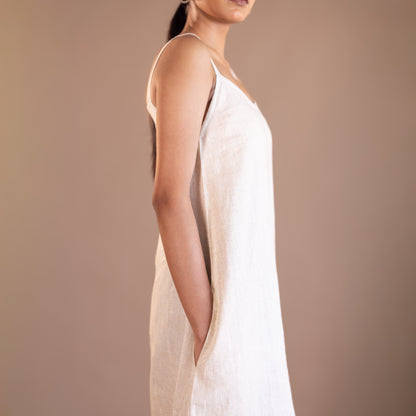 Woman wearing a beige slip dress against a brown background