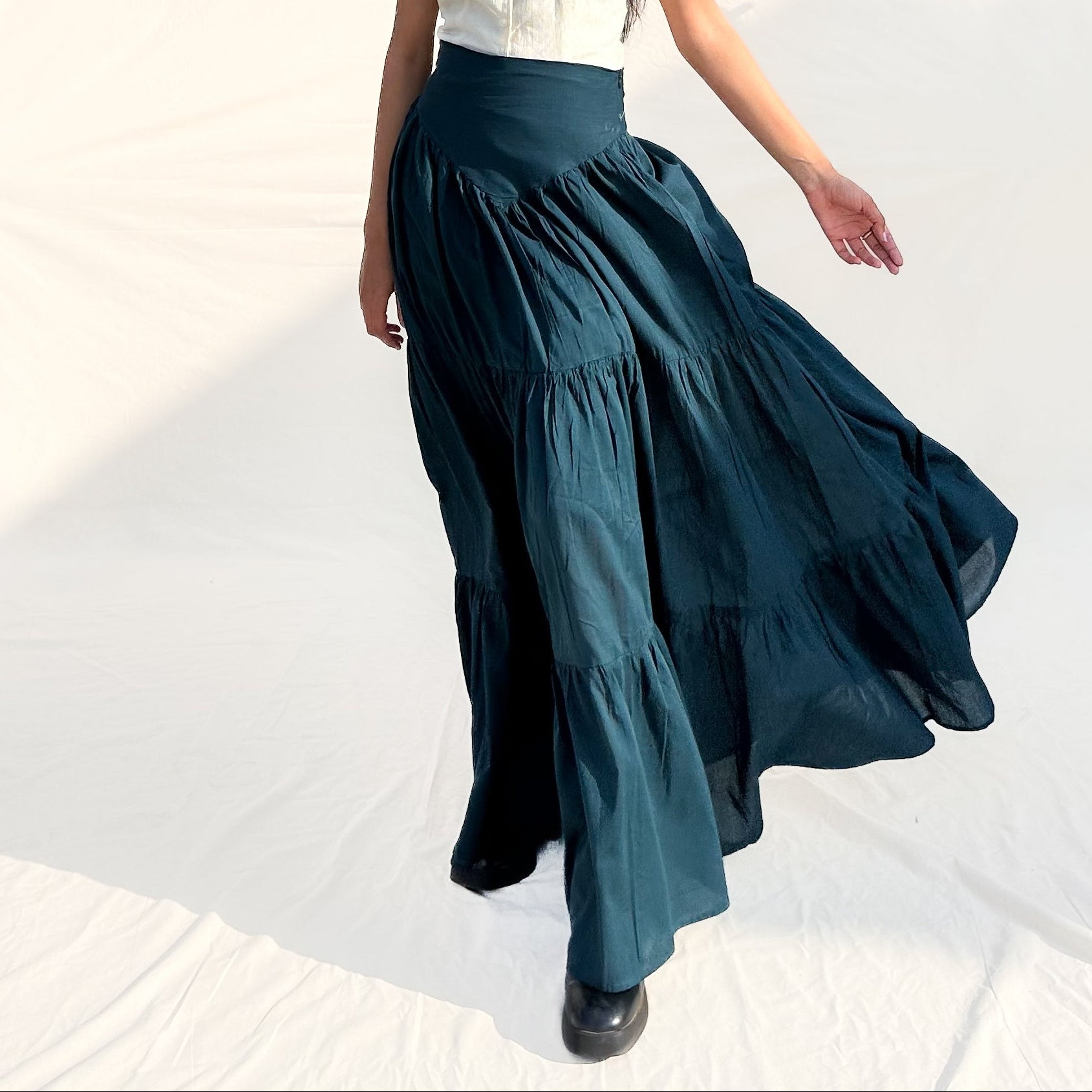 Woman wearing a white top and teal skirt on a white background