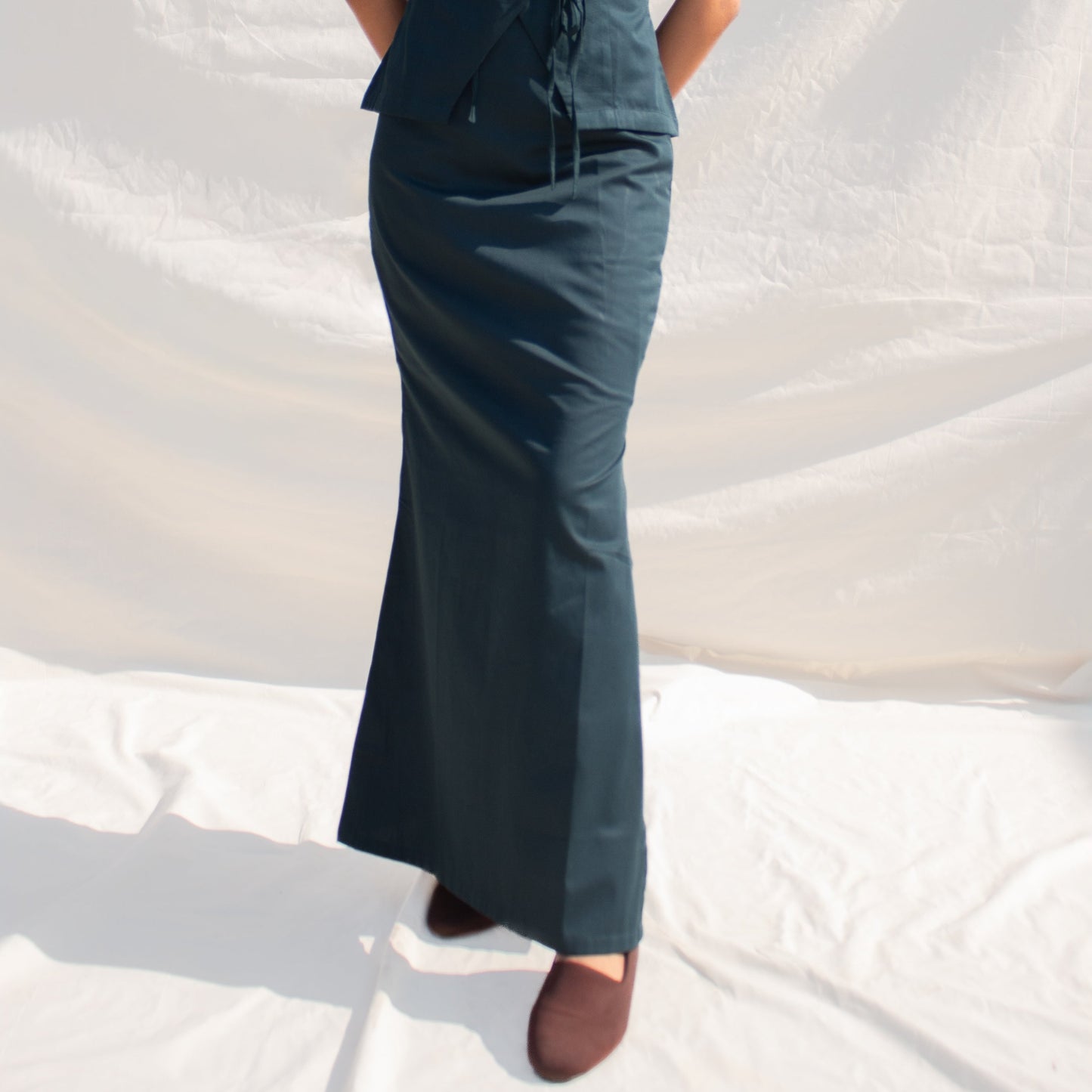 Woman wearing a sleeveless dark blue dress against a white background